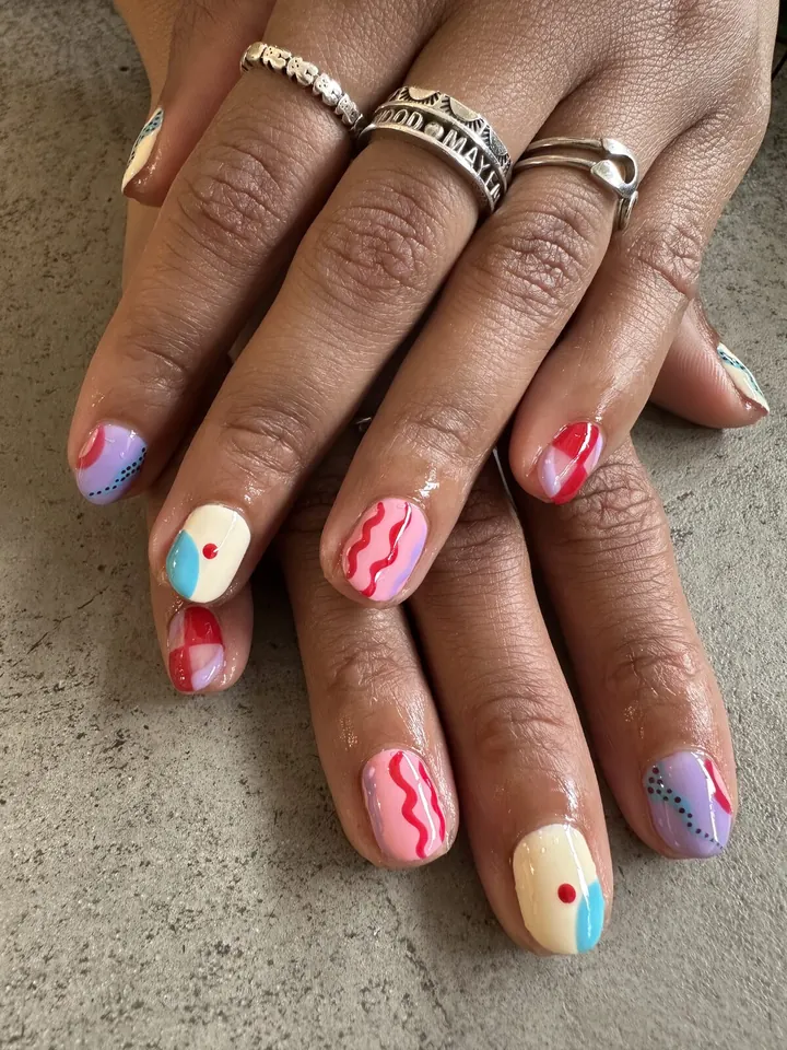 Uñas cortas con diseños de colores: ondas rosas, puntos y lila